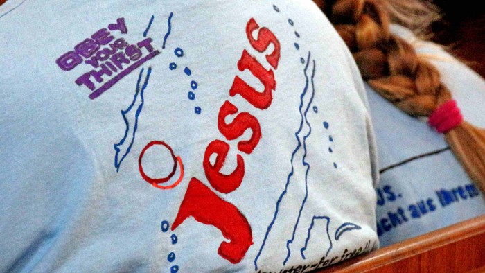 Das T-Shirt zeigt den Namen Jesus und ein Kreuz.