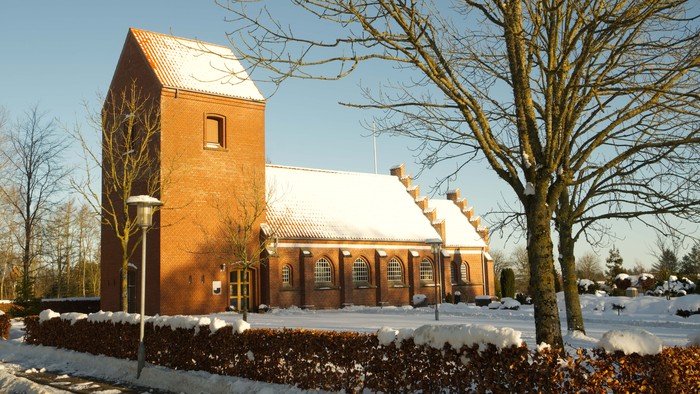 En rød kirke med sne på taget
