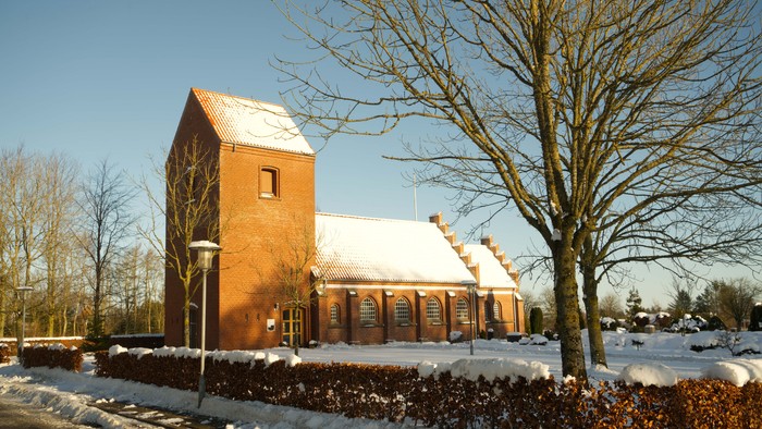 En rød kirke med sne på taget