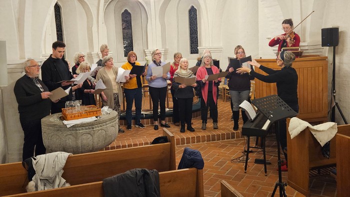 En kor sang i kirke med præst og musikere