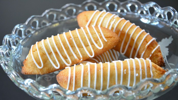 Gyldne wienerbrød dryppet med hvid glasur, elegant arrangeret på et dekorativt glastableau.