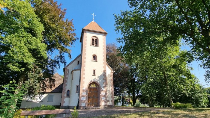 Kirche umgeben von Bäumen an einem sonnigen Tag.