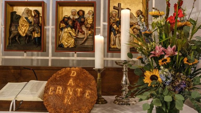 Eleganter Kirchenaltar mit religiöser Kunst, Kerzen, einer aufgeschlagenen Bibel und einem Strauß lebendiger Blumen.
