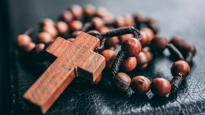 Holzkreuz und Rosenkranz auf schwarzer Oberfläche