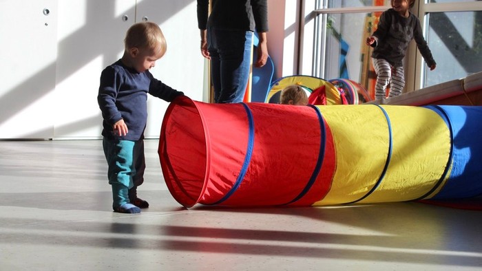 Kinder, die in einem Indoor-Spielbereich mit bunten aufblasbaren Tunneln spielen.