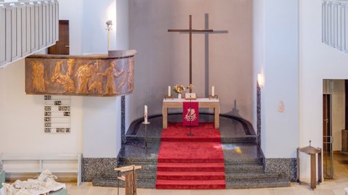 Die Kirche hat einen hohen Altar mit Kreuz und farbenfrohen Fenstern