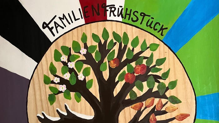 Bunter Kreis mit Baum und Schneemann, beschriftet mit 