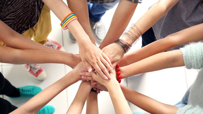 Eine Gruppe von Menschen, die sich im Kreis an den Händen halten und Einheit und Teamwork symbolisieren.