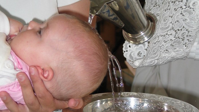 Ein Baby wird während eines zeremoniellen Rituals mit über den Kopf gegossenem Wasser getauft.
