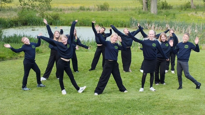 En gruppe af unge kvinder udfører en dans i en park.
