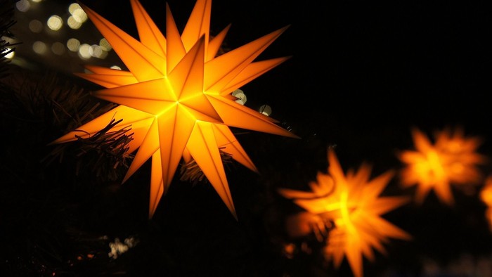 Helle, orange, sternförmige Lichter, die im dunklen Nachthimmel hängen.
