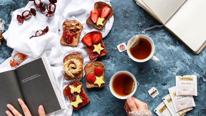 Ein gemütliches Frühstücksszenario mit Toast, Tee und einem aufgeschlagenen Buch.