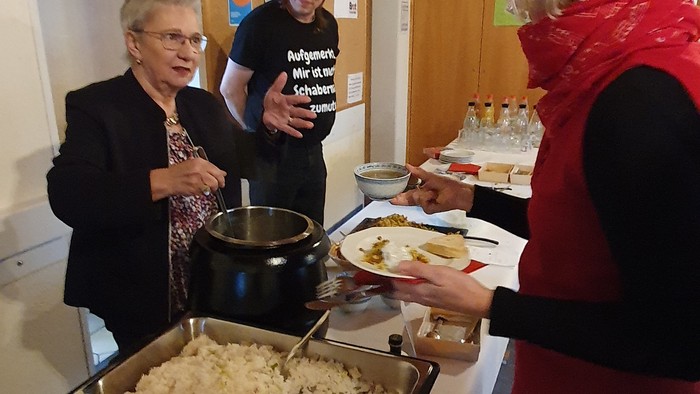 Personen, die bei einer gesellschaftlichen Veranstaltung Essen im Buffet-Stil servieren, mit verschiedenen Gerichten auf den Tischen.