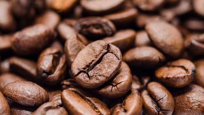 Afrundede, ristede kaffebønner tæt samlet med synlige bønnemærker.