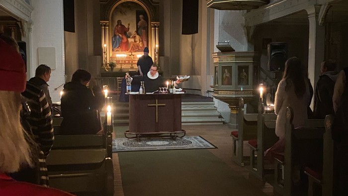 En kirke med folk, lys og alter.