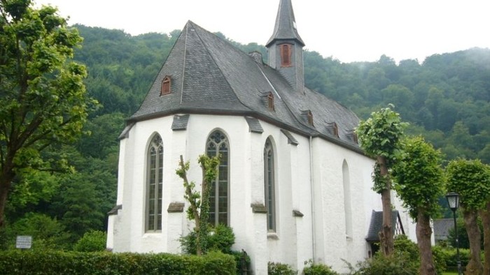 Weiße Kirche mit hohem Turm in grünem Landschaftsbereich