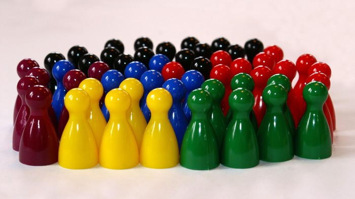 Bunte Plastikfiguren, nach Farben in Reihen angeordnet, mit Ober- und Unterteilen.