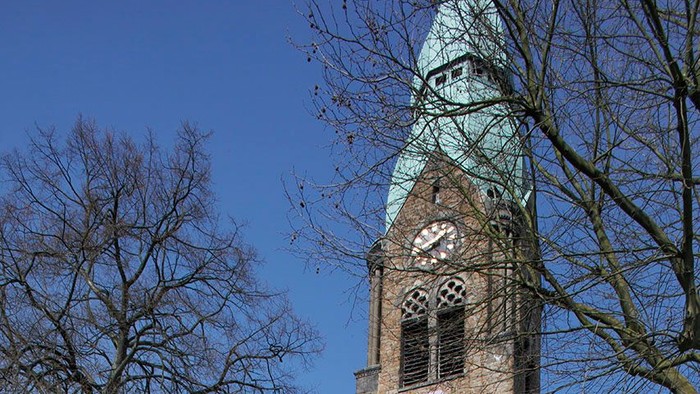 Die Christuskirche in Bochum Gerthe. Vom Kirchturm hängt eine Fahne mit der Aufschrift: 