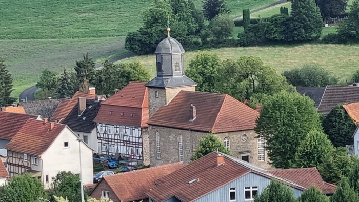 Ein malerisches Dorf mit roten Dächern und einem Kirchturm inmitten von grünen Feldern