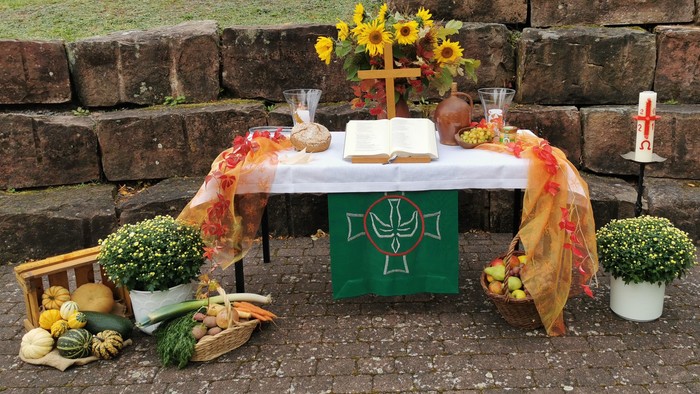 Ein festlich gedeckter Tisch mit Blumen, Obst und Gemüse vor einer Steinmauer