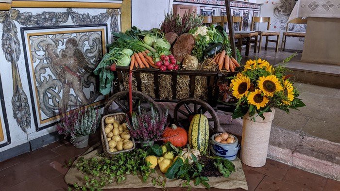 Ein Gemüsewagen mit verschiedenen frischen Produkten und einer Blumenvase in einem Raum mit Fliesenwänden