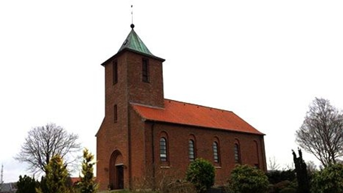 En rød murstenskirke med spiret og klokketårn.