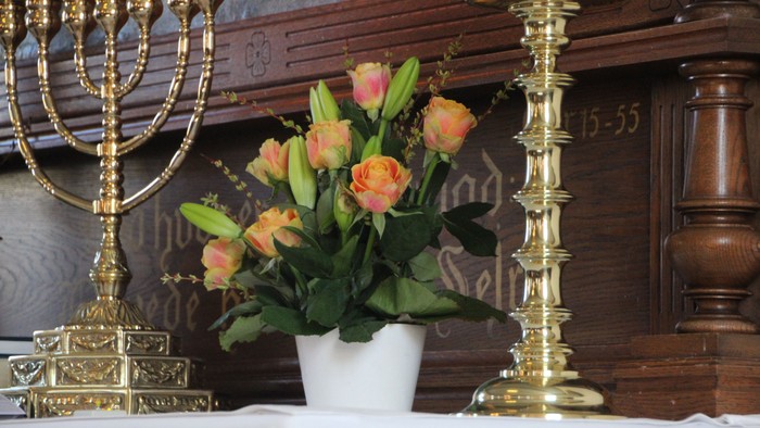 Guldsmykket meneskelys og blomsterarrangement på bord