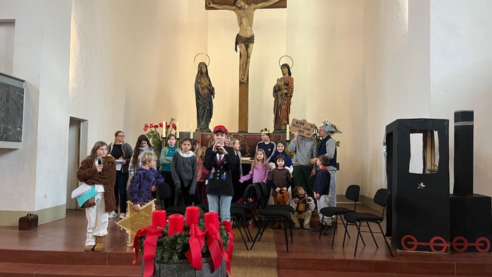 Eine Gruppe von Menschen, darunter Kinder, versammelt sich in einer Kirche zu einem festlichen oder religiösen Anlass mit geschmückten Altargegenständen.