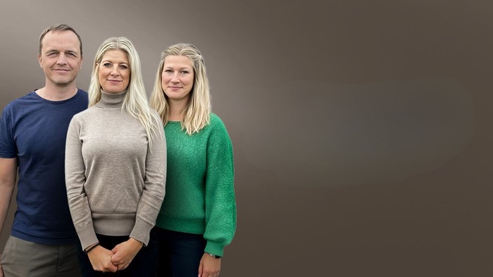 Tre personer står sammen i afslappet tøj foran en ensfarvet gradientbaggrund.