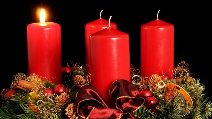 Drei brennende rote Kerzen auf Weihnachtsdekoration