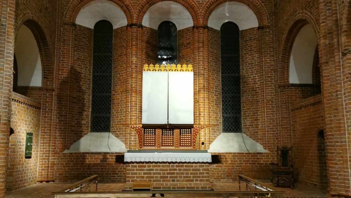 Elegant indendørs gårdhave med moderne belysning og murstensbuer omkring et reflekterende vandparti.