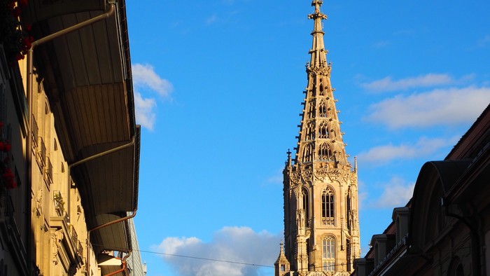 Gothischer Kirchturm ragt über Kopfsteinpflasterstraße
