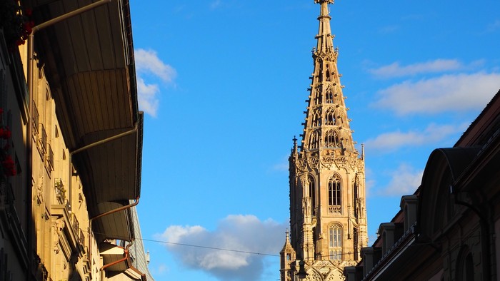Gothischer Kirchturm ragt über Kopfsteinpflasterstraße