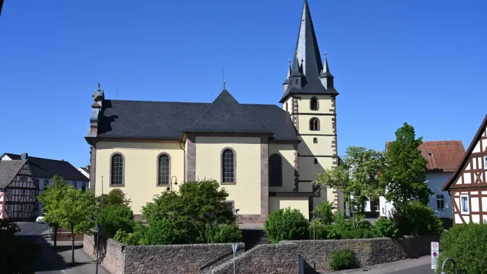 Eine malerische Kirche mit hohem Kirchturm in einem idyllischen, grünen europäischen Dorf.