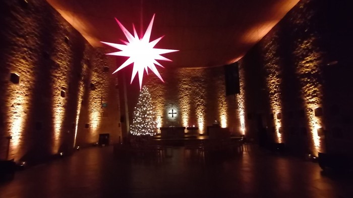 Großer Weihnachtsstern in Kirche mit beleuchtetem Christbaum