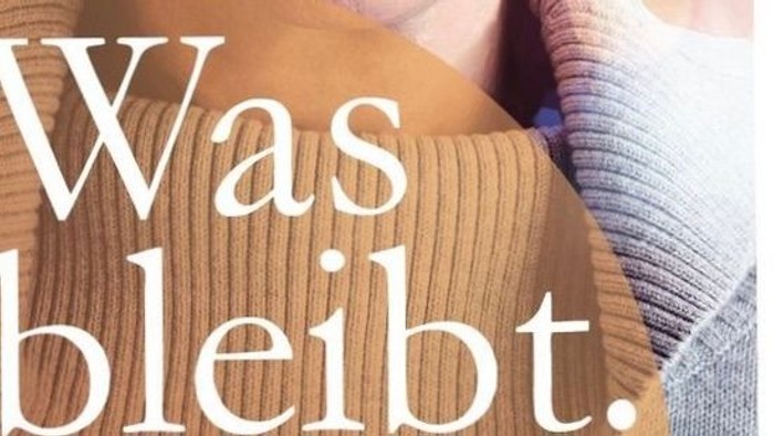Gemütlicher Pullover im Nahaufnahme mit teilweise sichtbarem deutschen Text *„Was bleibt“* auf hellem Hintergrund.
