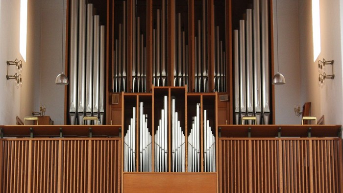 Elegant pibeorgel med træbeklædning og flere rækker af polerede metalpiber i en rolig omgivelse.