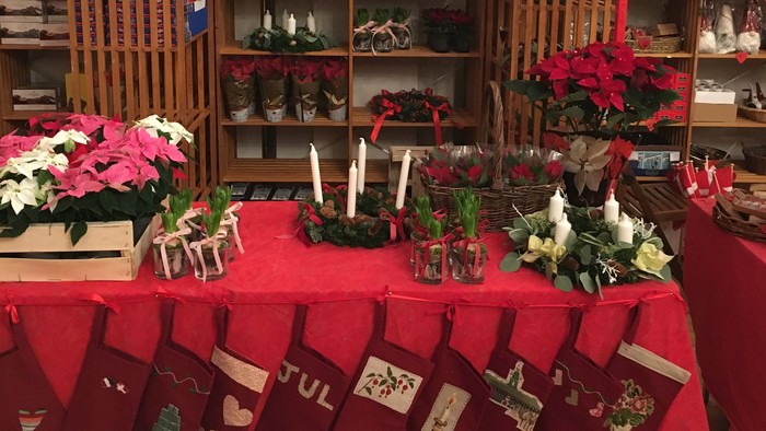 En juleudstilling med strømper, blomster og pynt.