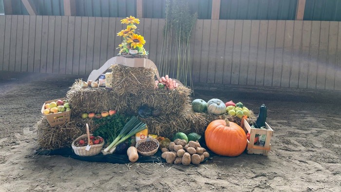 Eine Erntedekoration mit Obst, Gemüse und Blumen, arrangiert auf Heuballen.