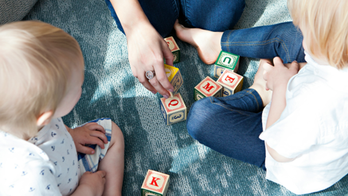 Kinder, die mit Bauklötzen auf einem Teppich spielen.