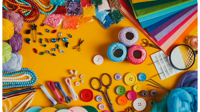 Bunte Bastelutensilien und Materialien auf gelber Oberfläche