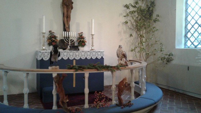 En lille kapel med alter, lysestage, og dyr i træ.