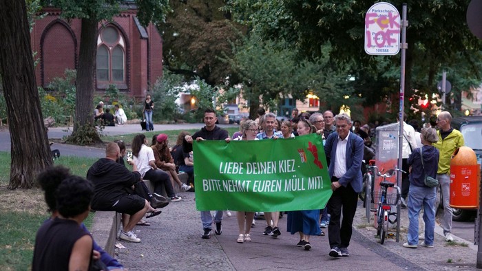 Menschen vor der Apostel-Paulus-Kirche tragen ein Transparent mit Text