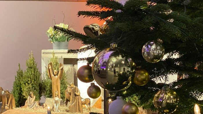Ein Weihnachtsbaum mit bunten Kugeln und einer Miniaturlandschaft darunter