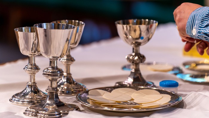 Silver chalices and plate with bread on white cloth
