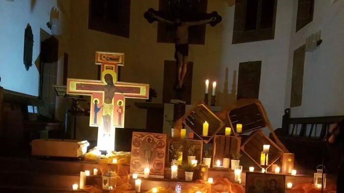 Ein feierlicher Kirchenaltar, geschmückt mit Kerzen, hölzernen Kreuzen und religiösen Ikonen während einer Abendandacht.
