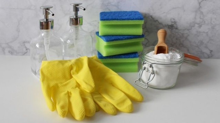 Reinigungsutensilien wie Handschuhe, Schwämme, Spülmittel und Binden auf einer Arbeitsplatte