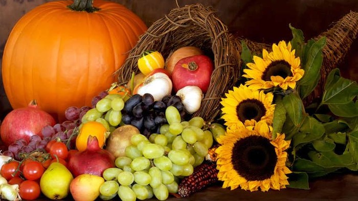 Bunter Herbstkorb mit Kürbis, Äpfeln, Trauben, Sonnenblumen und mehr