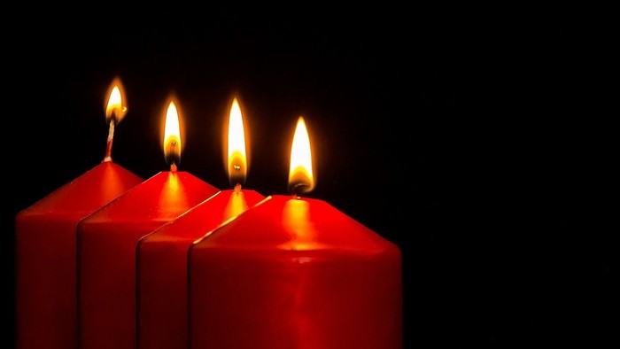 Vier brennende rote Kerzen vor schwarzem Hintergrund