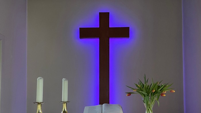 Ein Altar mit Kreuz, Kerzen und Blumen.